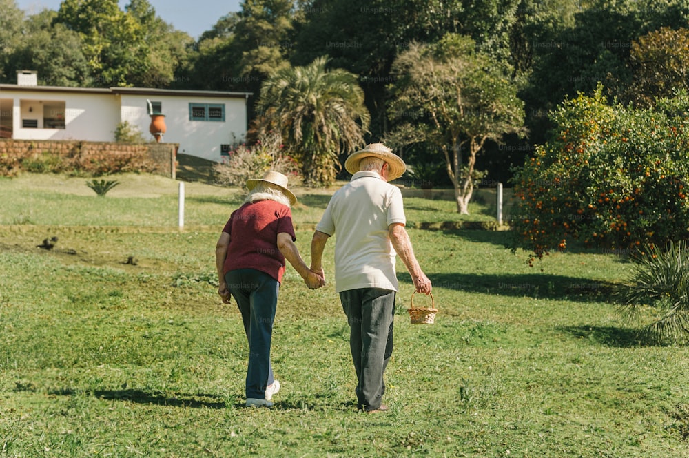 a couple of people walking across a lush green field