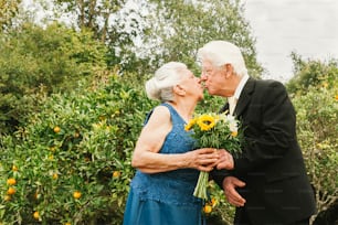 an older couple kissing each other in front of trees