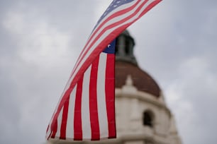 a large american flag flying in front of a building