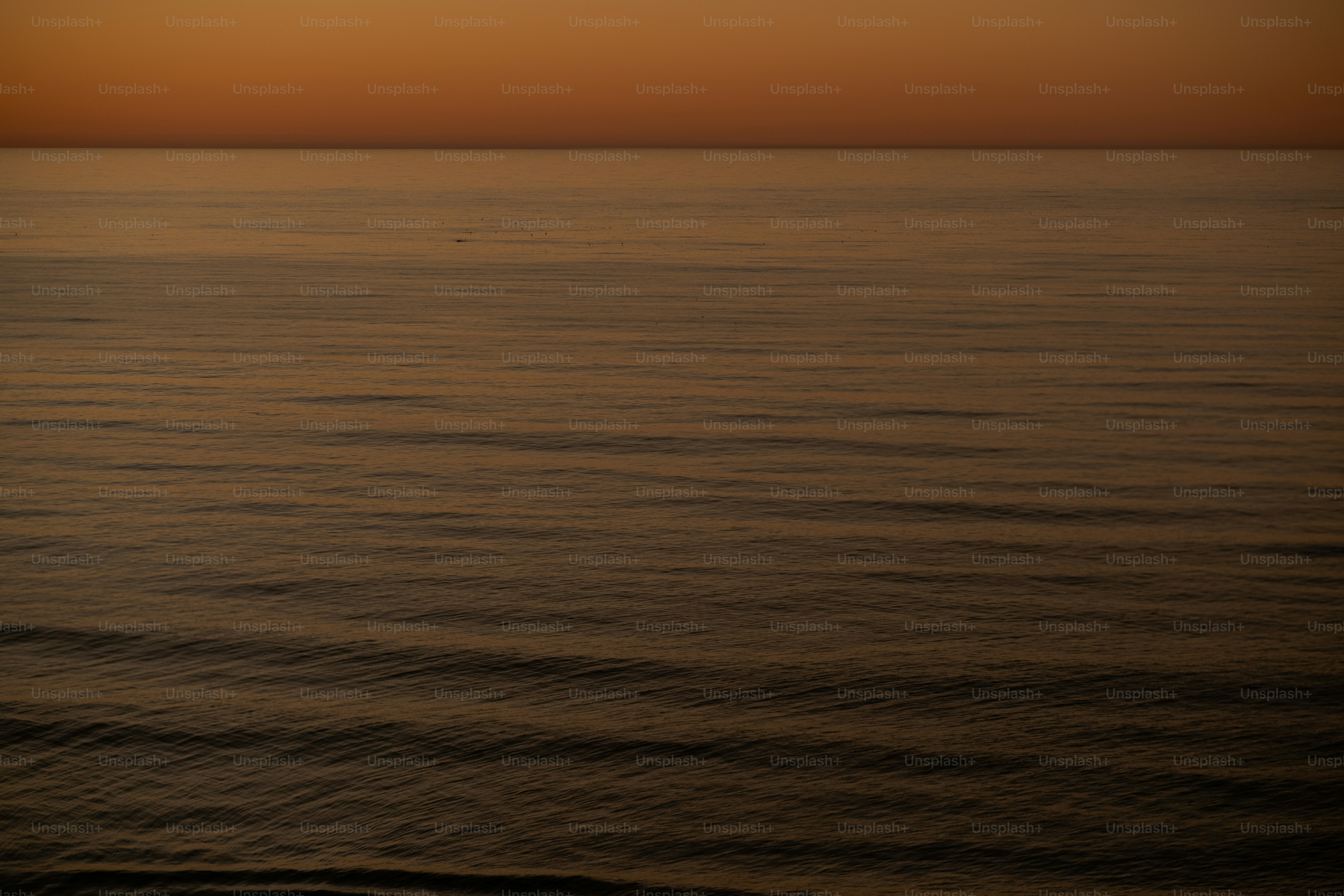 a large body of water with a sunset in the background