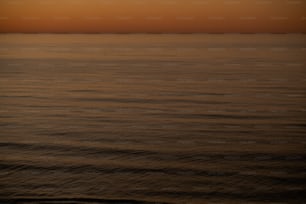 ein großes Gewässer mit einem Sonnenuntergang im Hintergrund