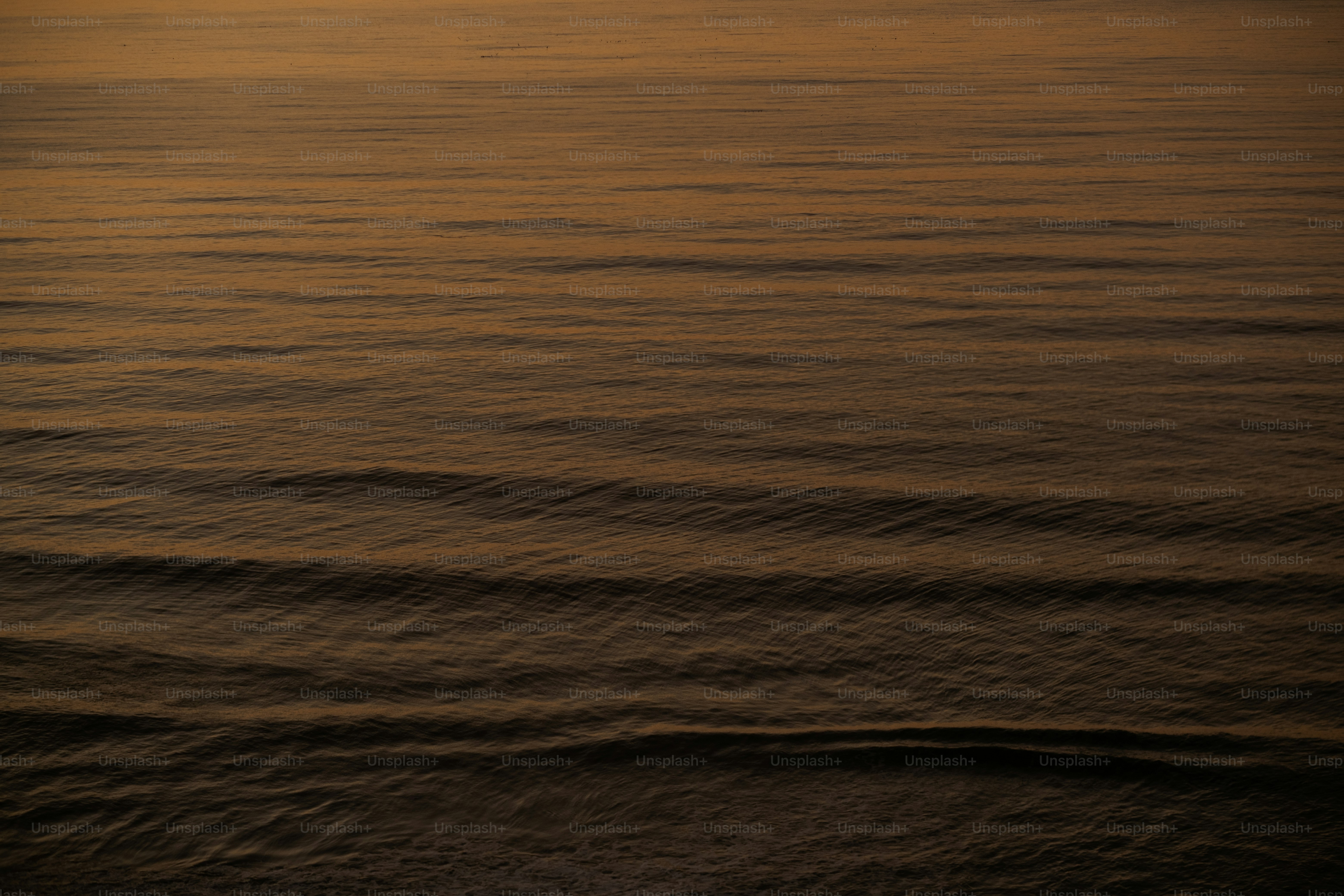 a large body of water with a sunset in the background
