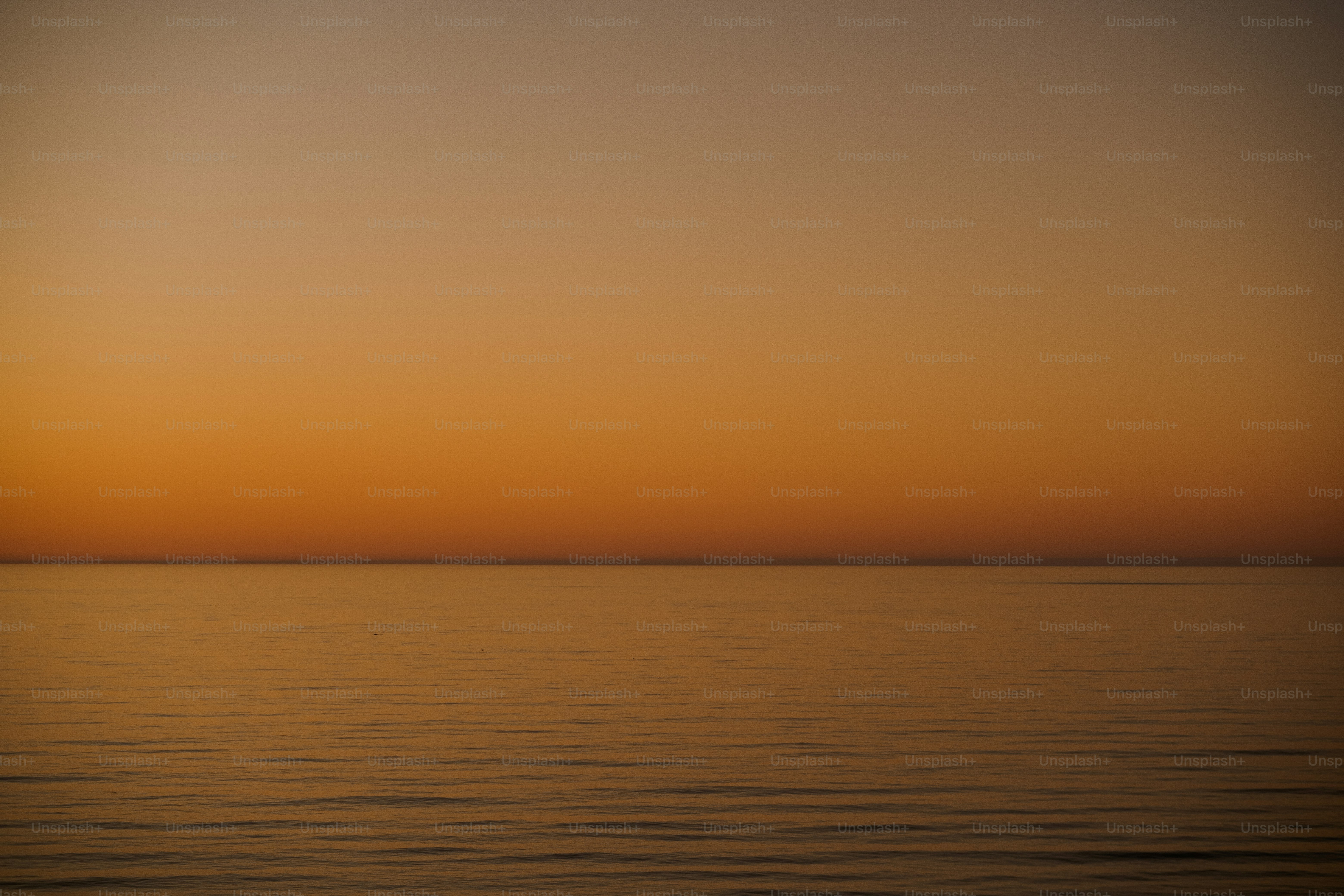 a large body of water with a sunset in the background