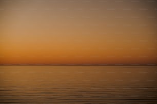 a large body of water with a sunset in the background