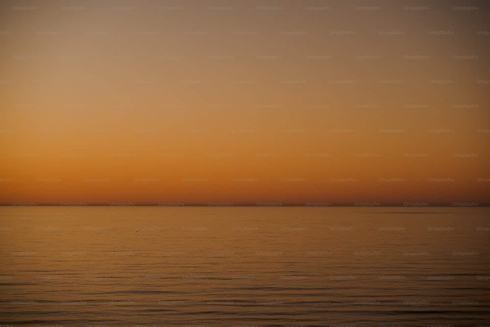 a large body of water with a sunset in the background