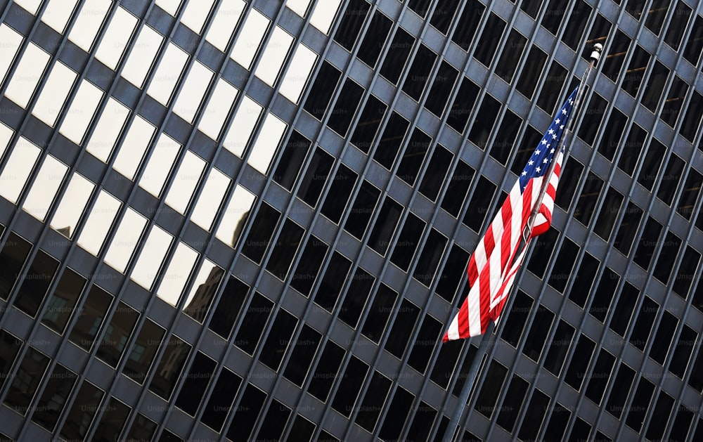 Una bandera estadounidense ondeando frente a un edificio alto