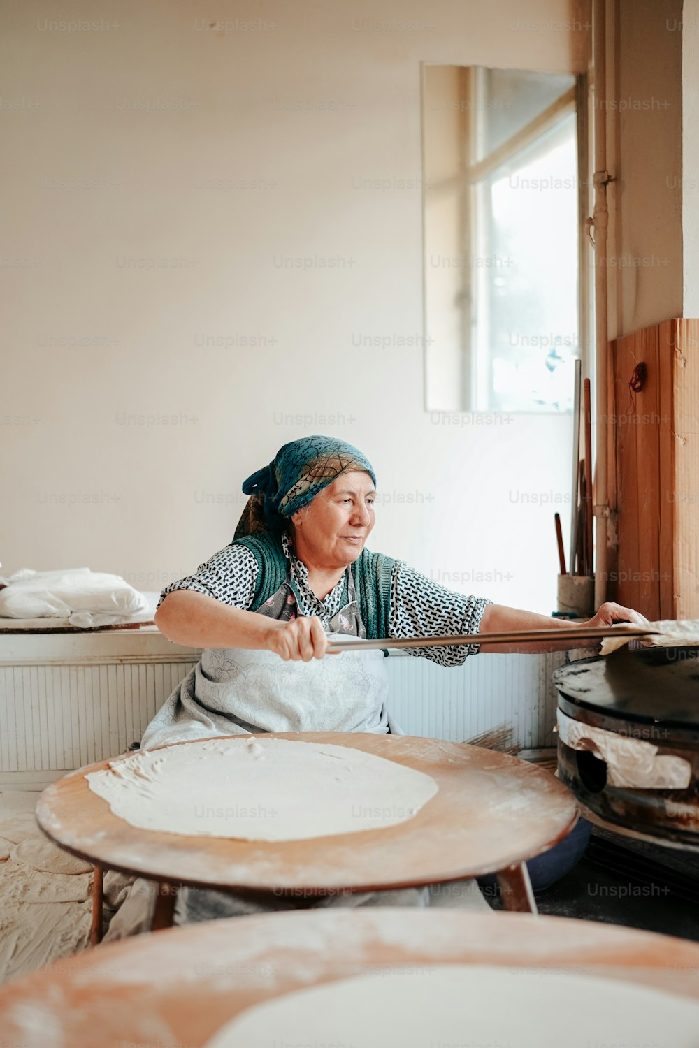 a woman in a kitchen making a pizza