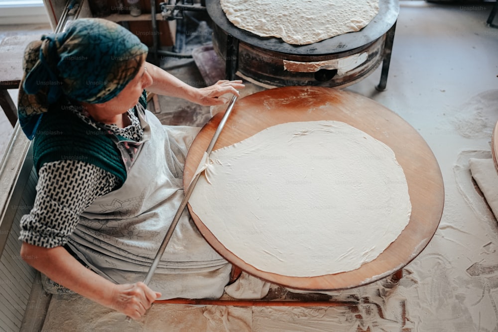 a woman is making a pizza in a kitchen