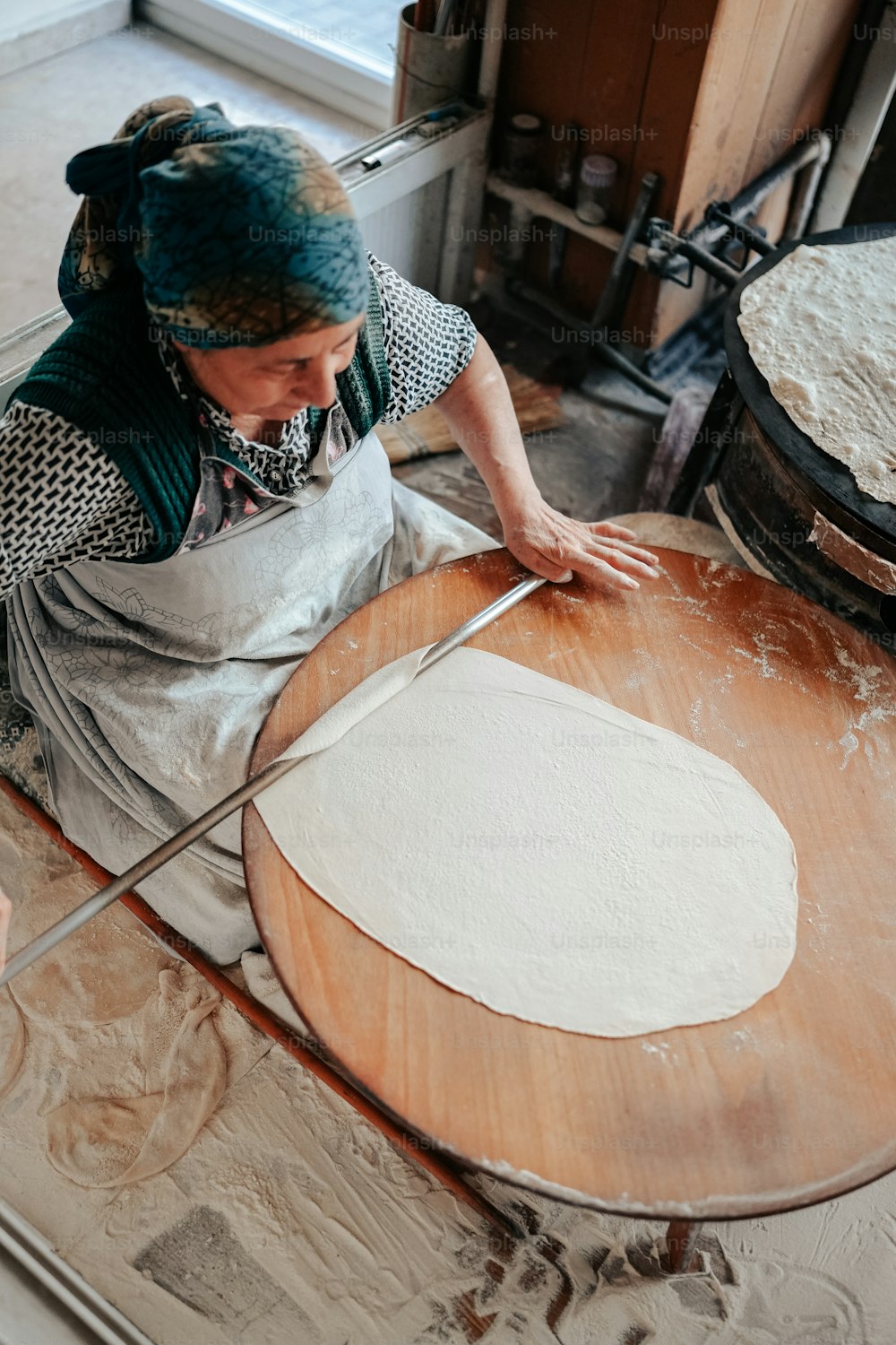 uma mulher em um avental está fazendo uma pizza