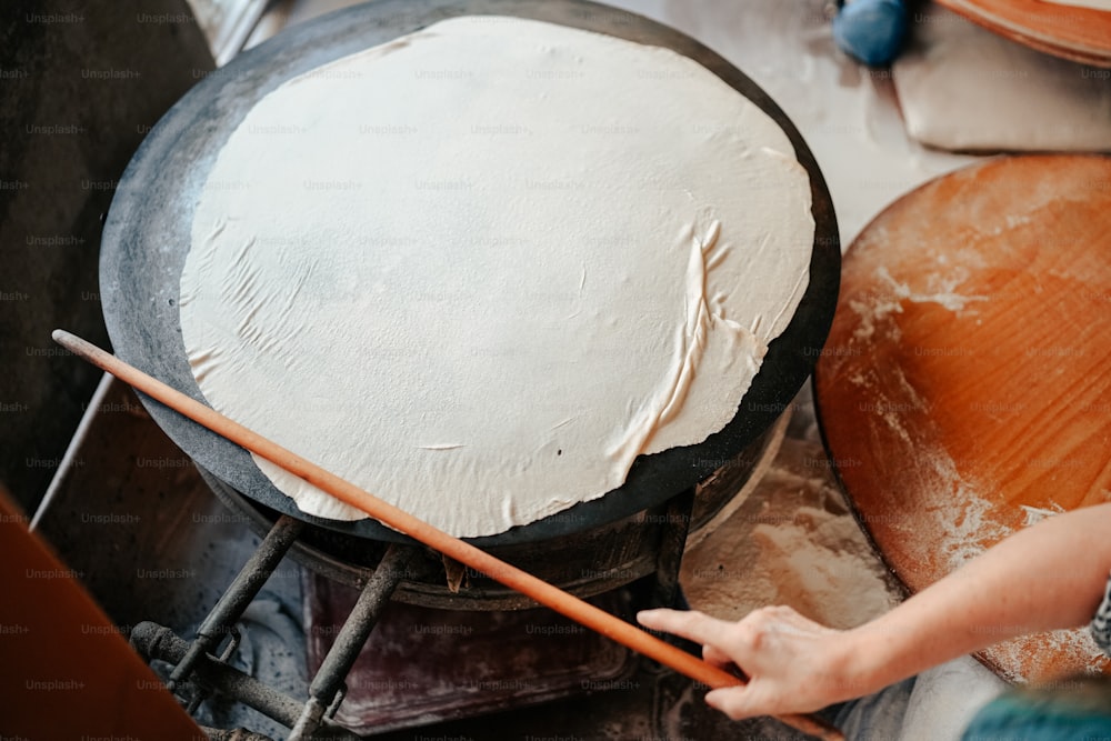 a person holding a wooden stick in front of a cake