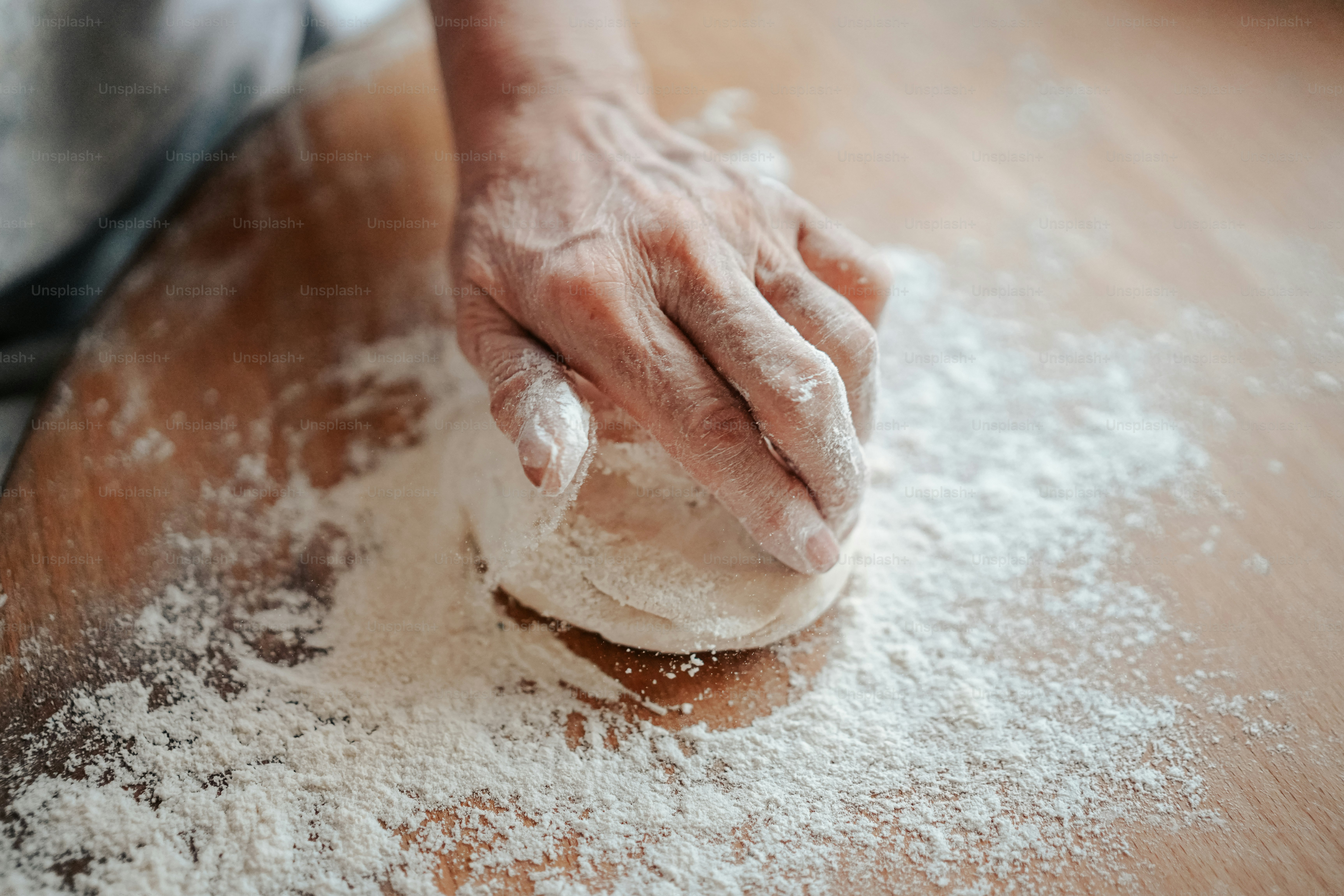 a person kneading dough on top of a wooden table