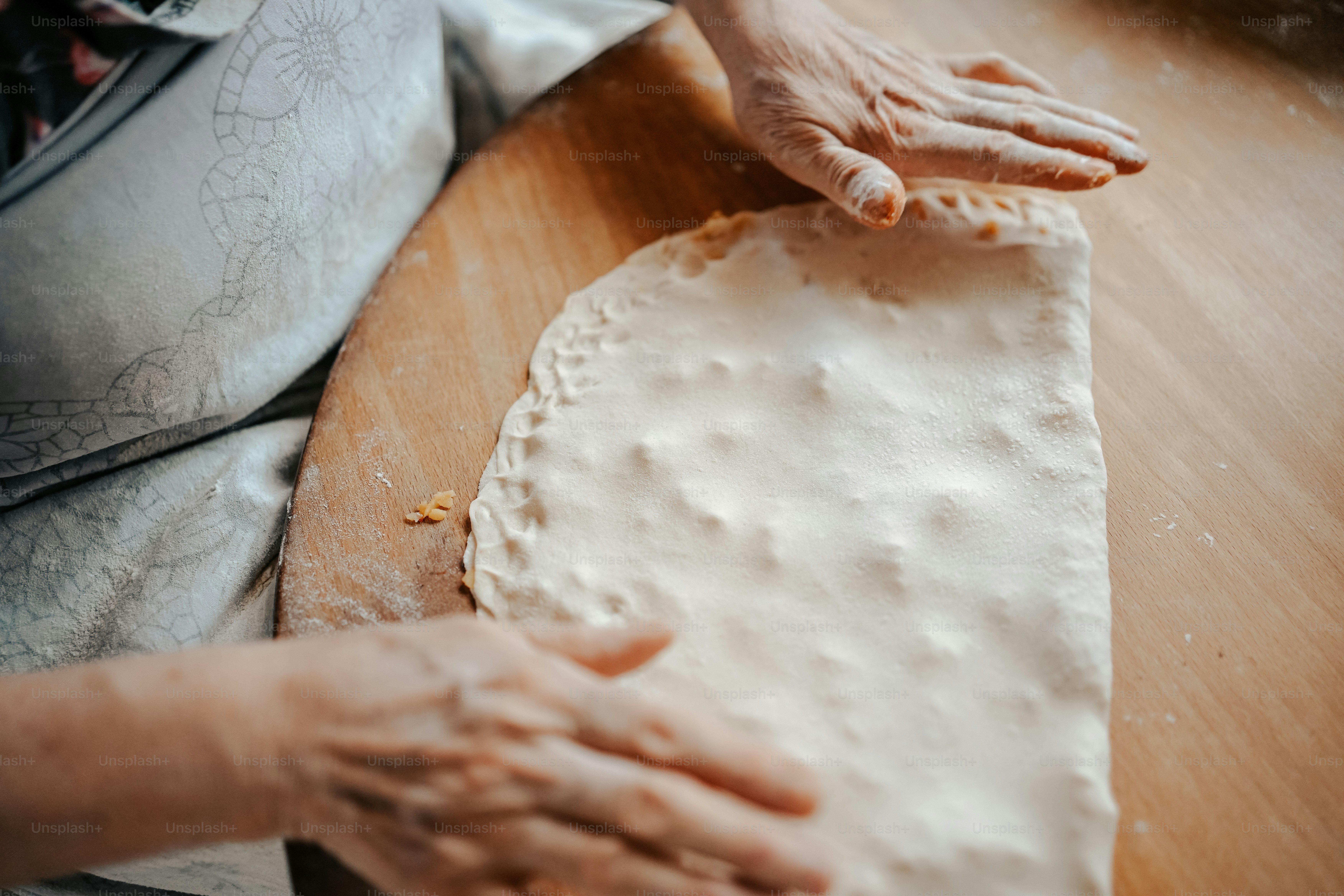 a person is kneading dough on a wooden table