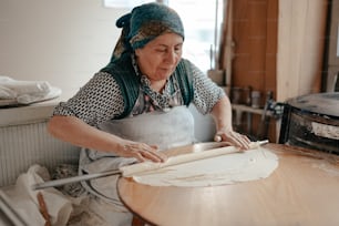 uma mulher está fazendo uma torta em uma mesa de madeira