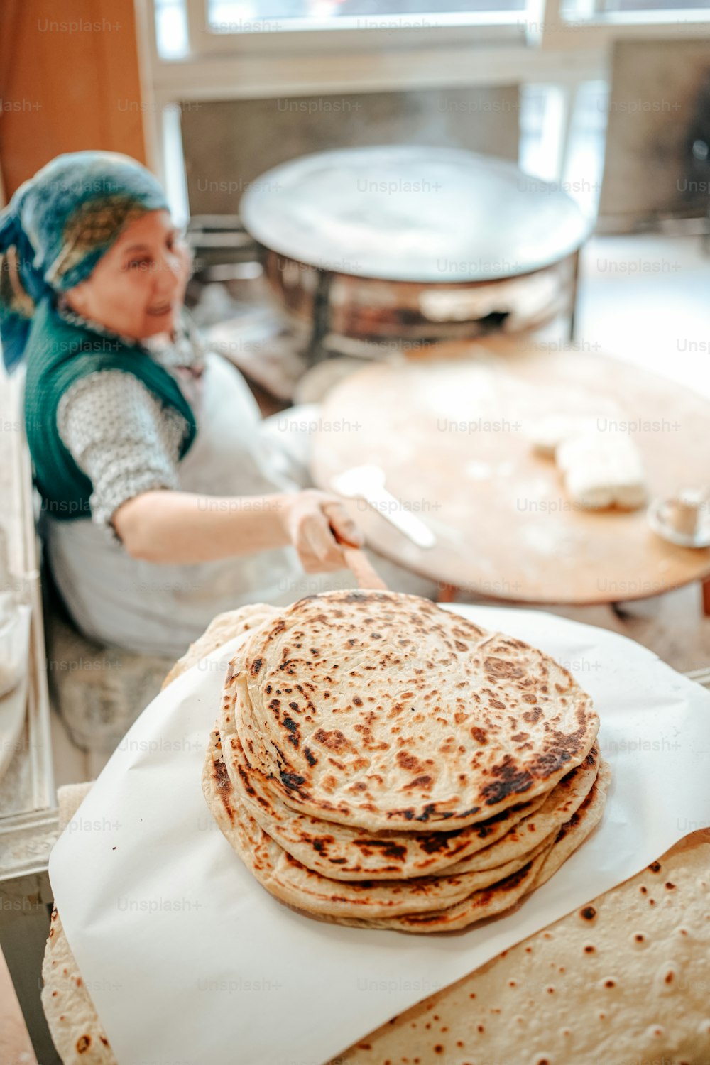 a woman in a kitchen with a stack of flatbreads