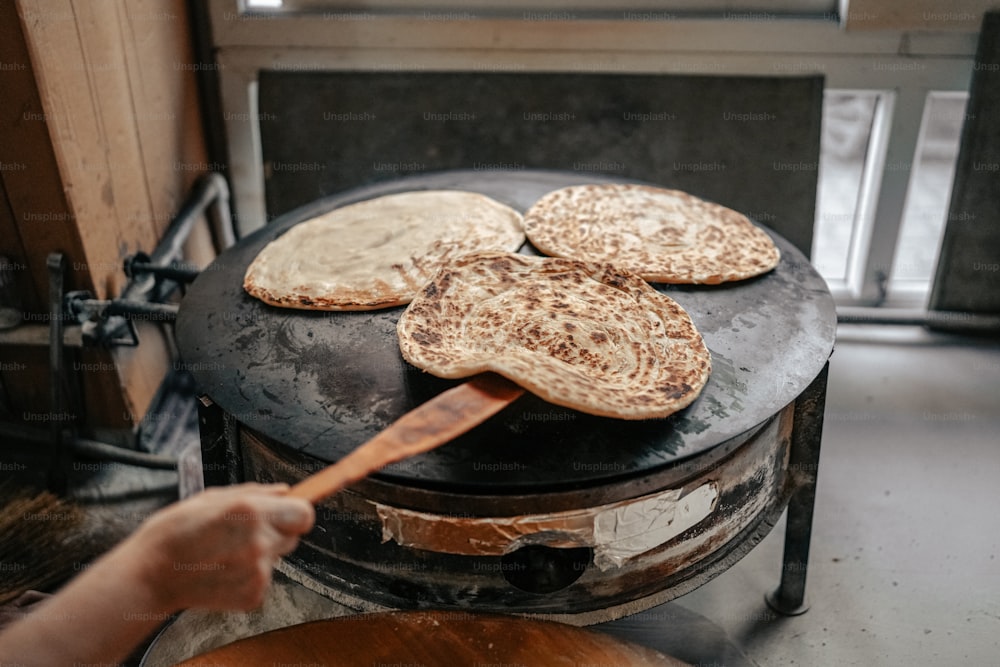 a person holding a wooden spatula over some food