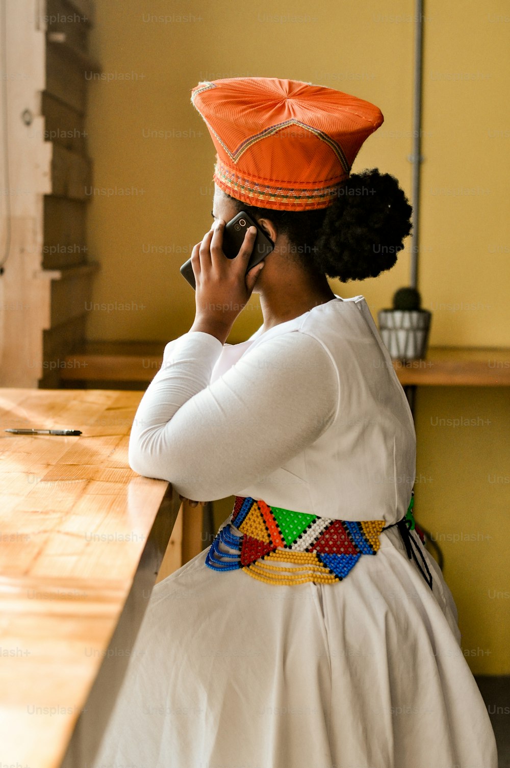 uma mulher sentada em uma mesa falando em um telefone celular