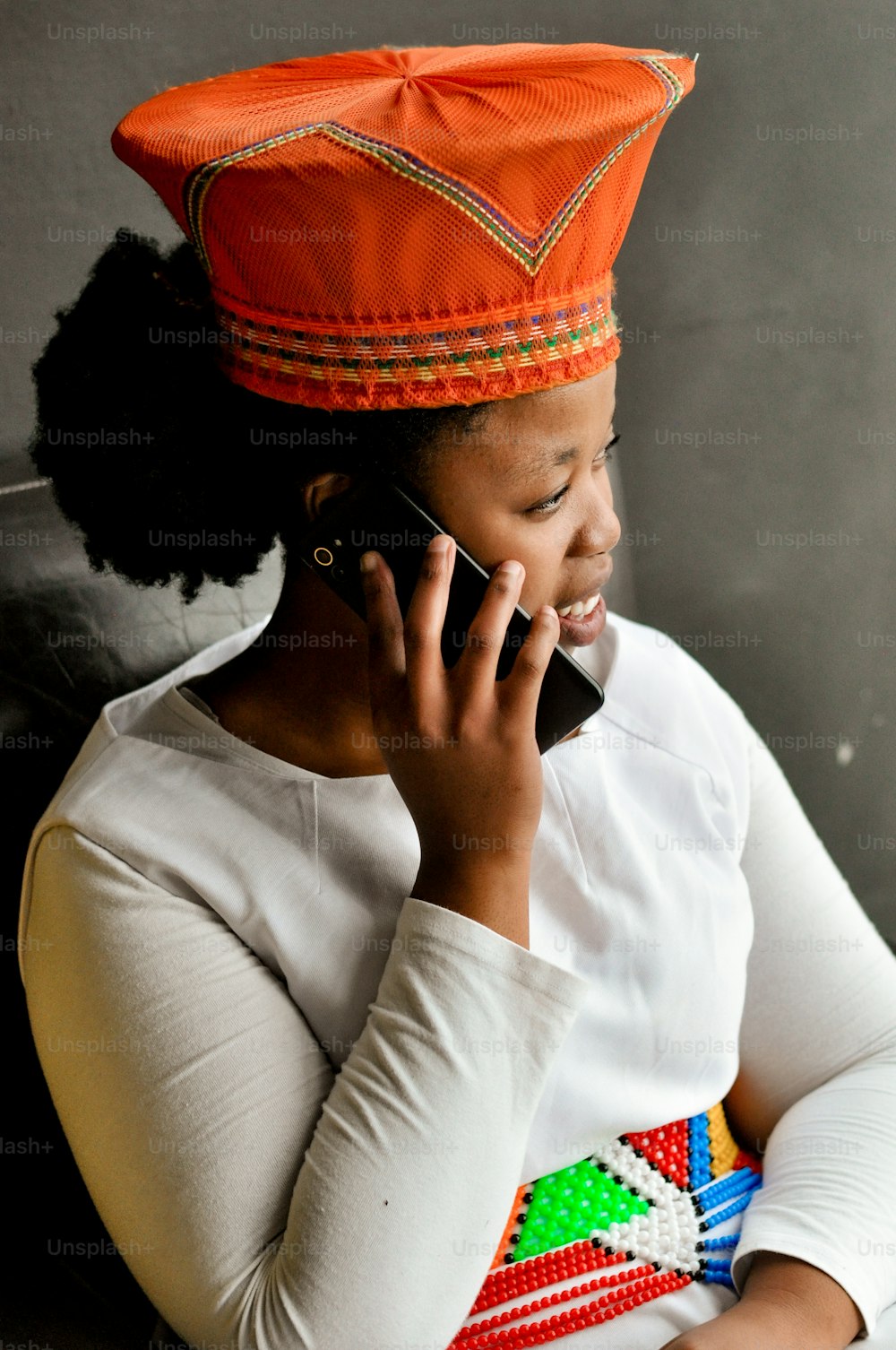 Eine Frau mit orangefarbenem Hut telefoniert