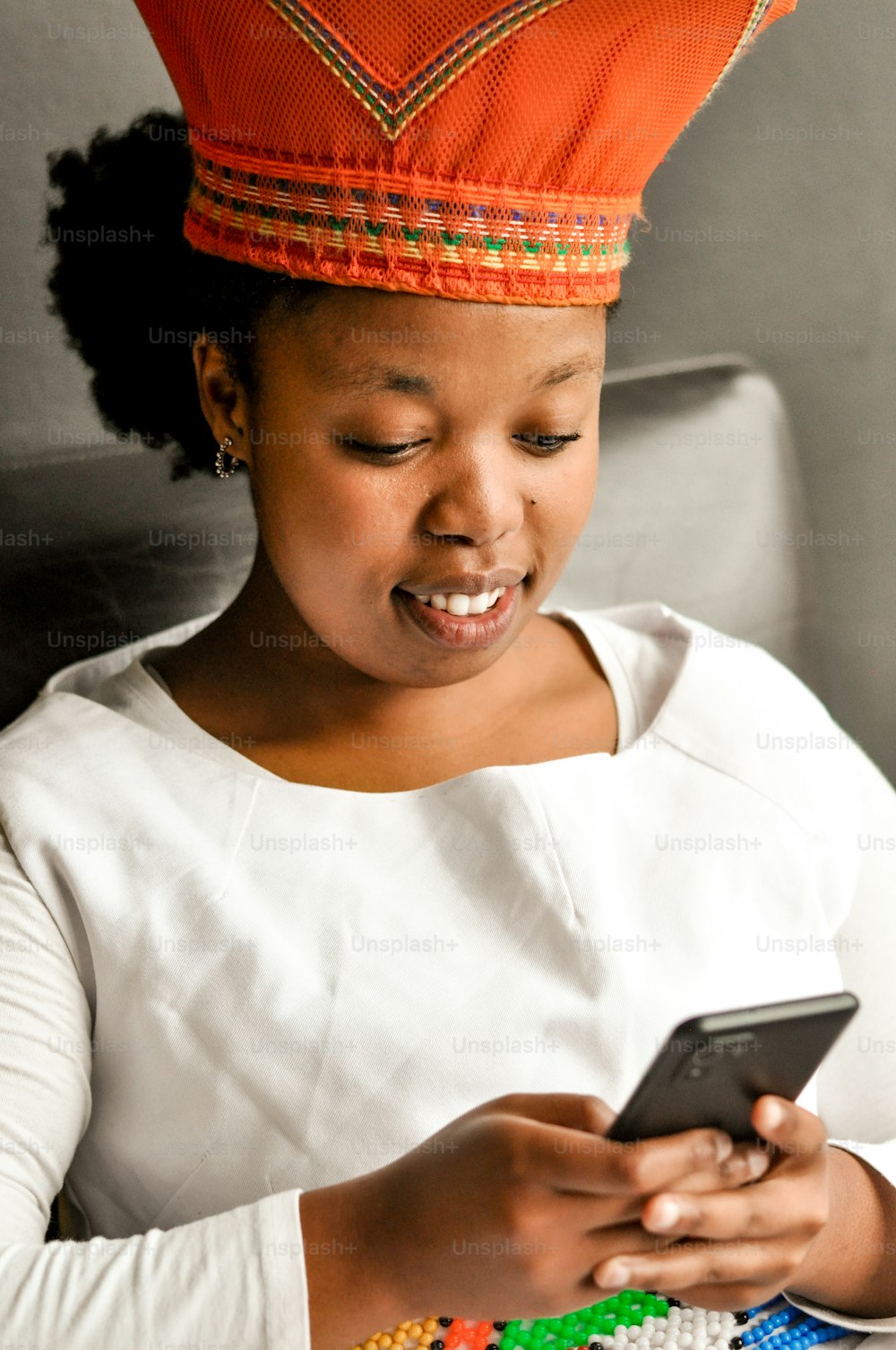 uma mulher em um chapéu vermelho olhando para um telefone celular