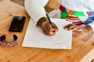 Una persona sentada en una mesa escribiendo en un pedazo de papel