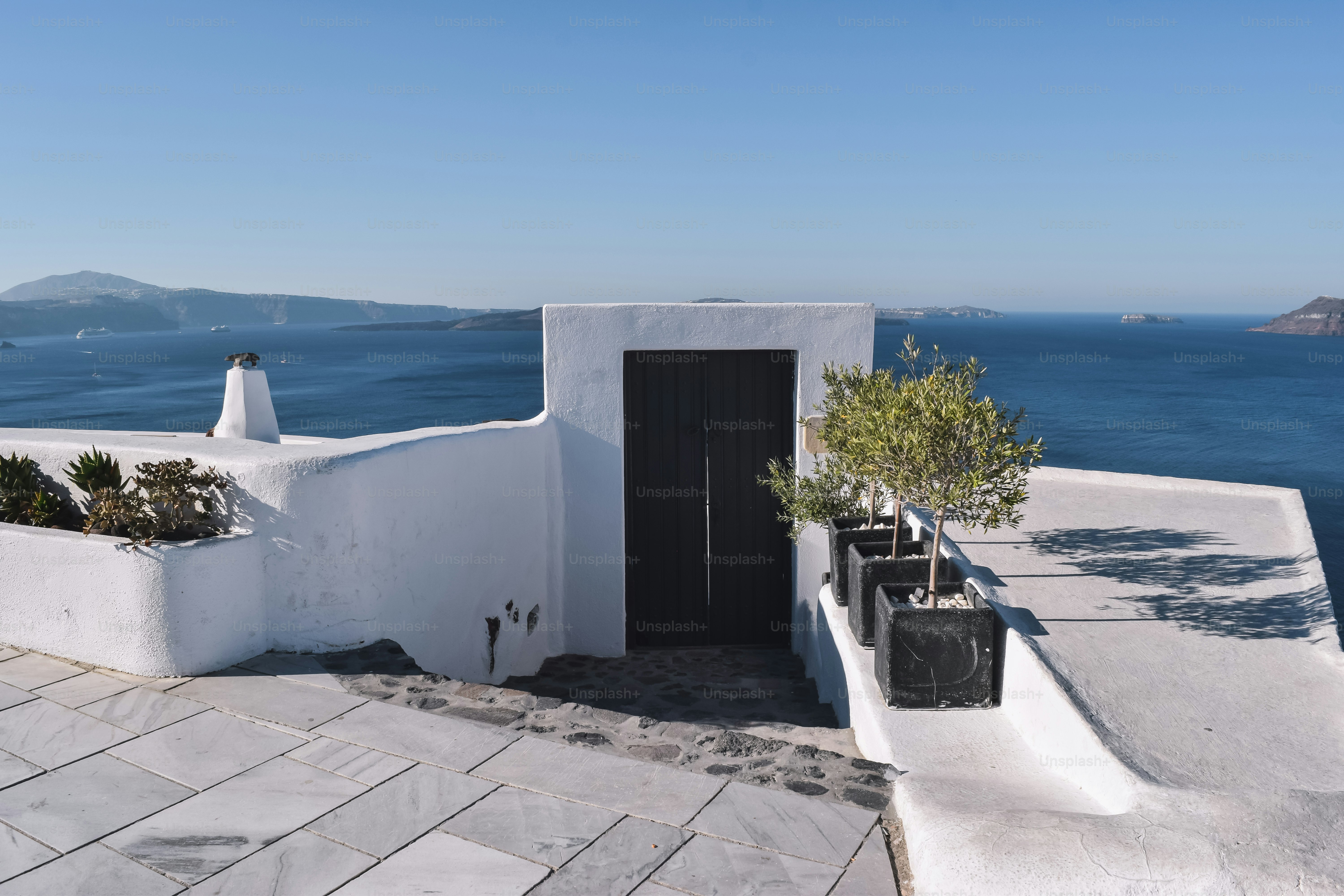 ein weißes Gebäude mit einer schwarzen Tür neben einem Gewässer