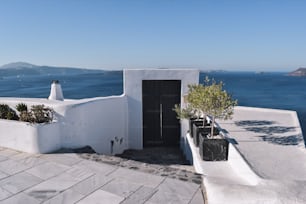 a white building with a black door next to a body of water
