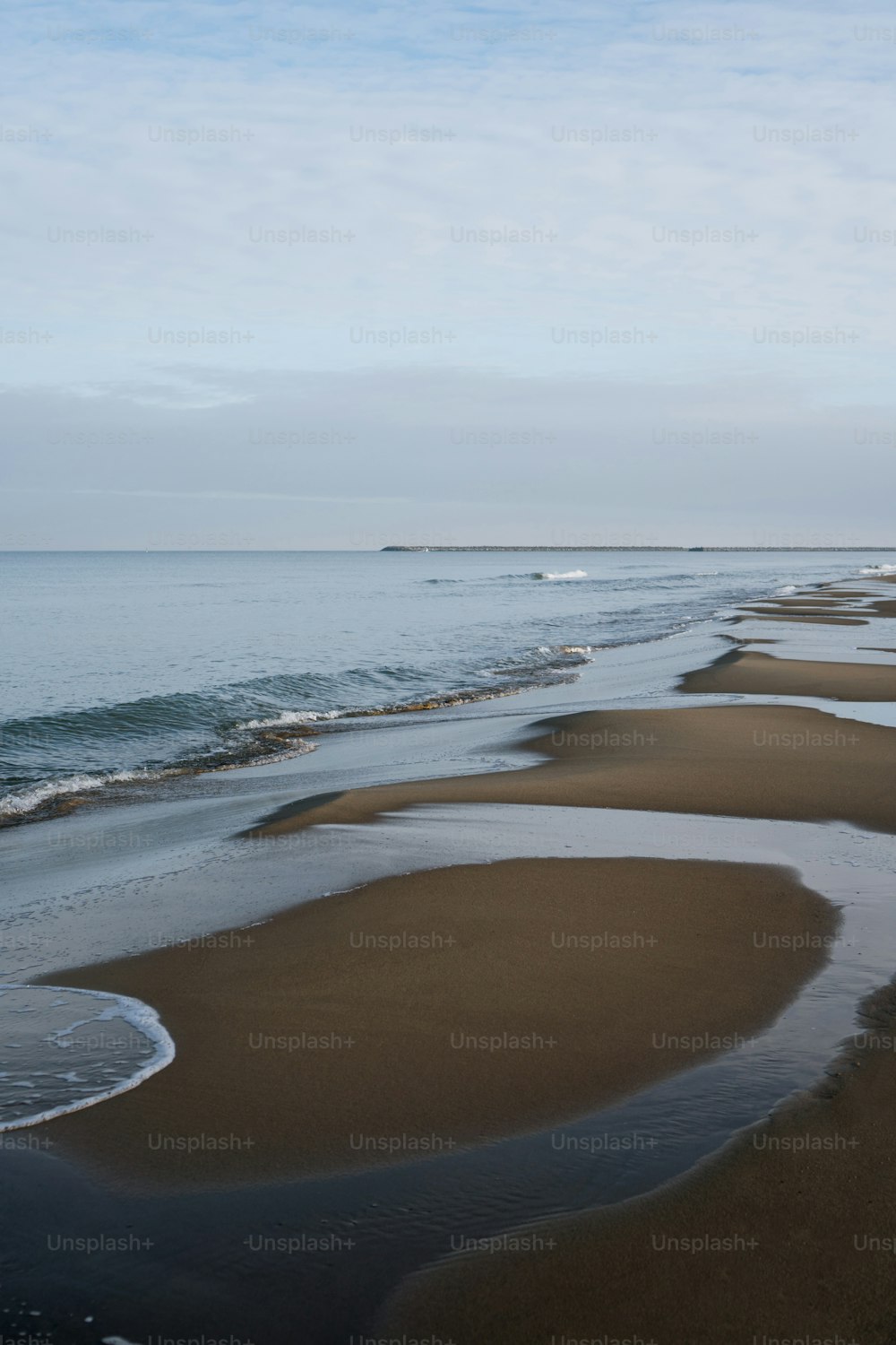 uma praia de areia com ondas que chegam à costa