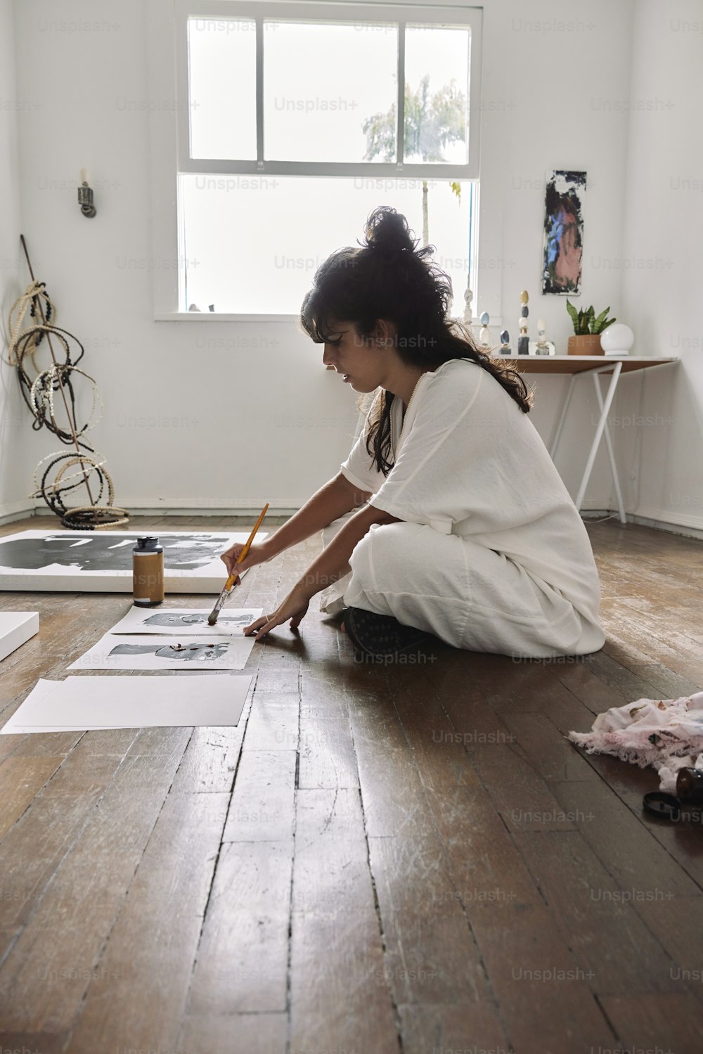 a woman sitting on the floor drawing on a piece of paper