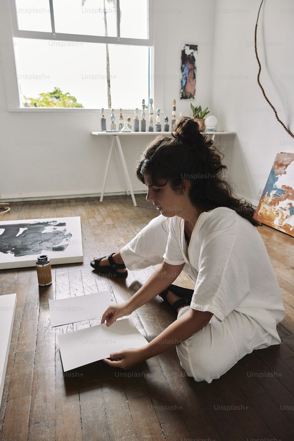 a woman sitting on the floor working on a piece of paper