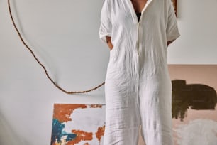 a woman in a white jumpsuit standing in front of a painting