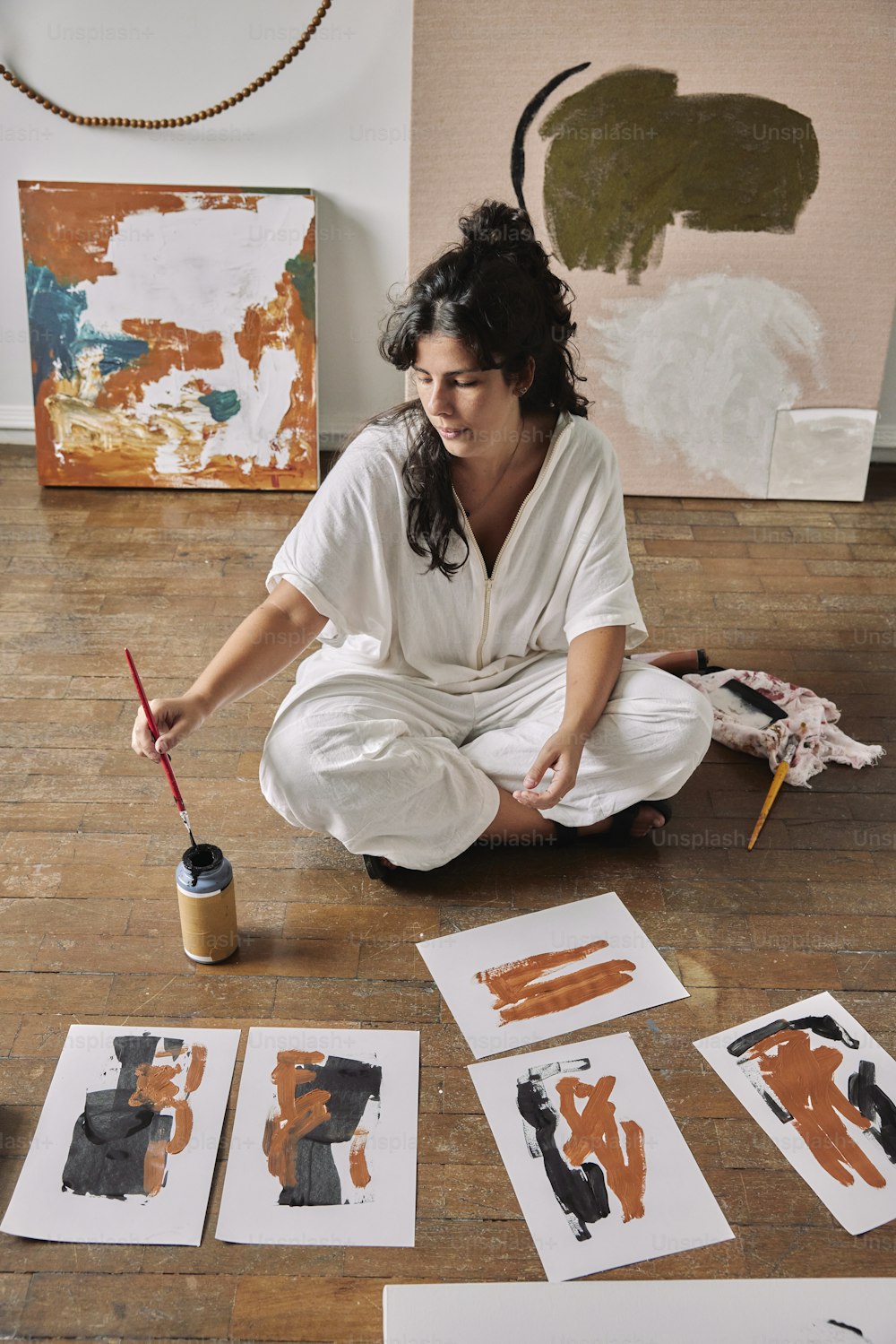 a woman is sitting on the floor painting