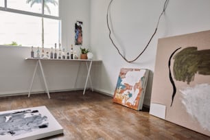 a room with a table and paintings on the floor