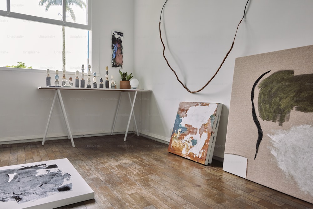 ein Raum mit Tisch und Gemälden auf dem Boden