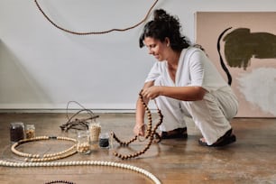 a woman kneeling on the floor next to a bunch of beads