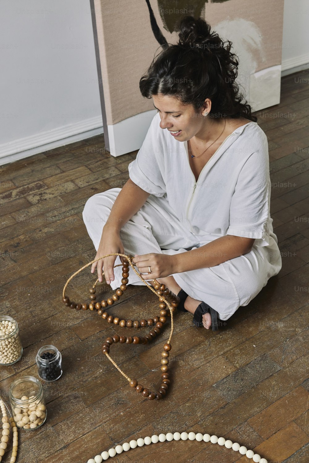 a woman is sitting on the floor making beads