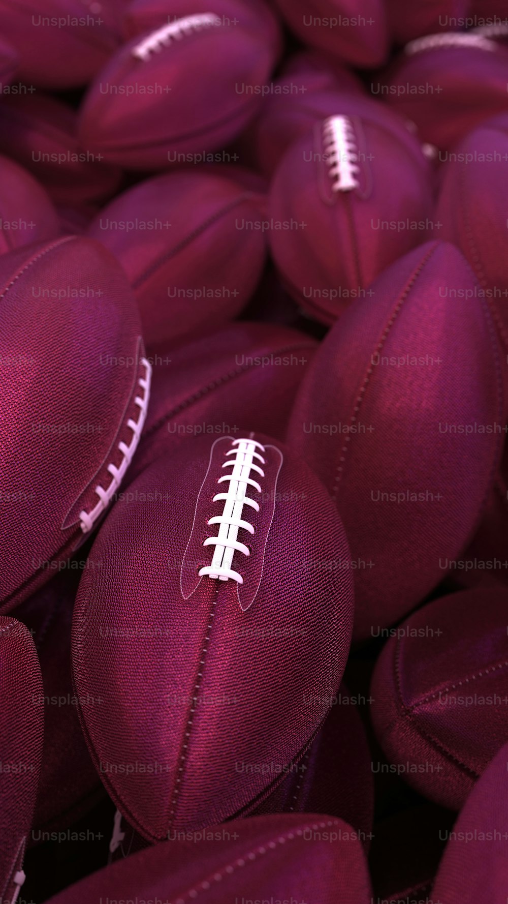 a pile of purple footballs with white stitching on them