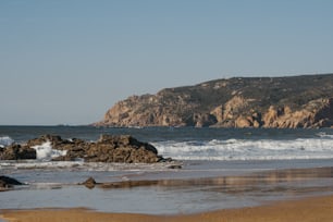 um grande corpo de água sentado ao lado de uma costa rochosa