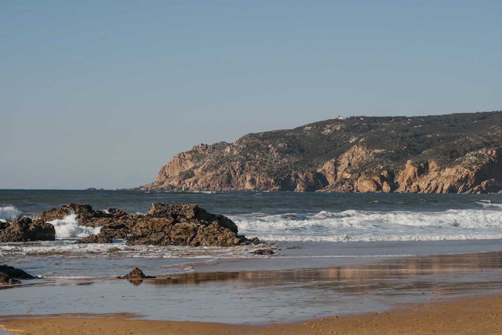um grande corpo de água sentado ao lado de uma costa rochosa