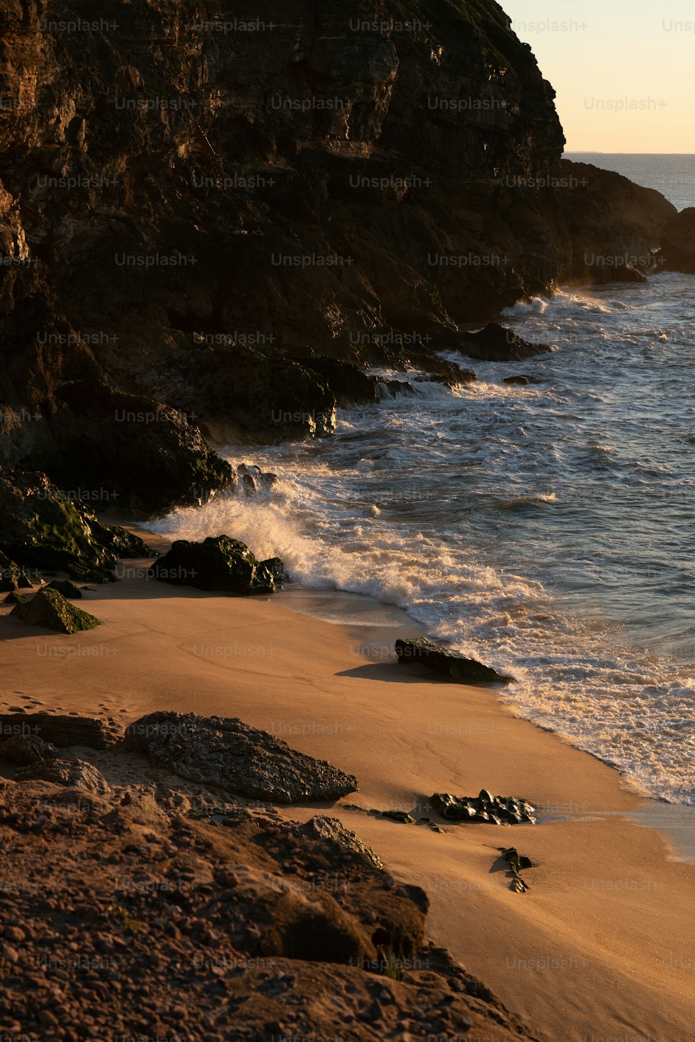 a sandy beach next to a rocky cliff