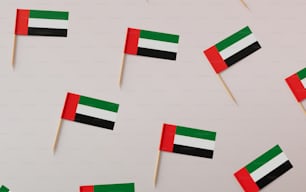 um grupo de pequenas bandeiras em palitos de dente em uma superfície branca