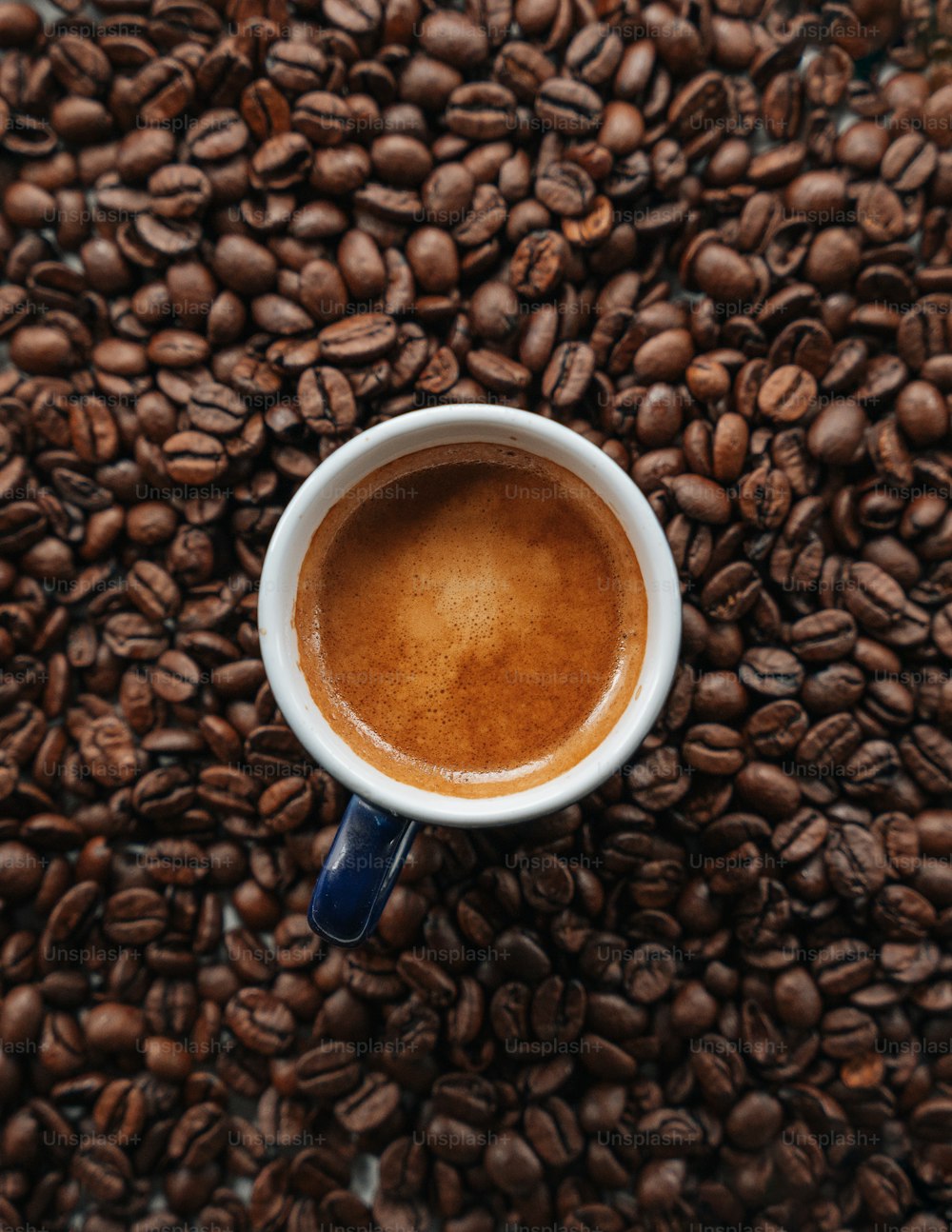 una taza de café encima de una pila de granos de café