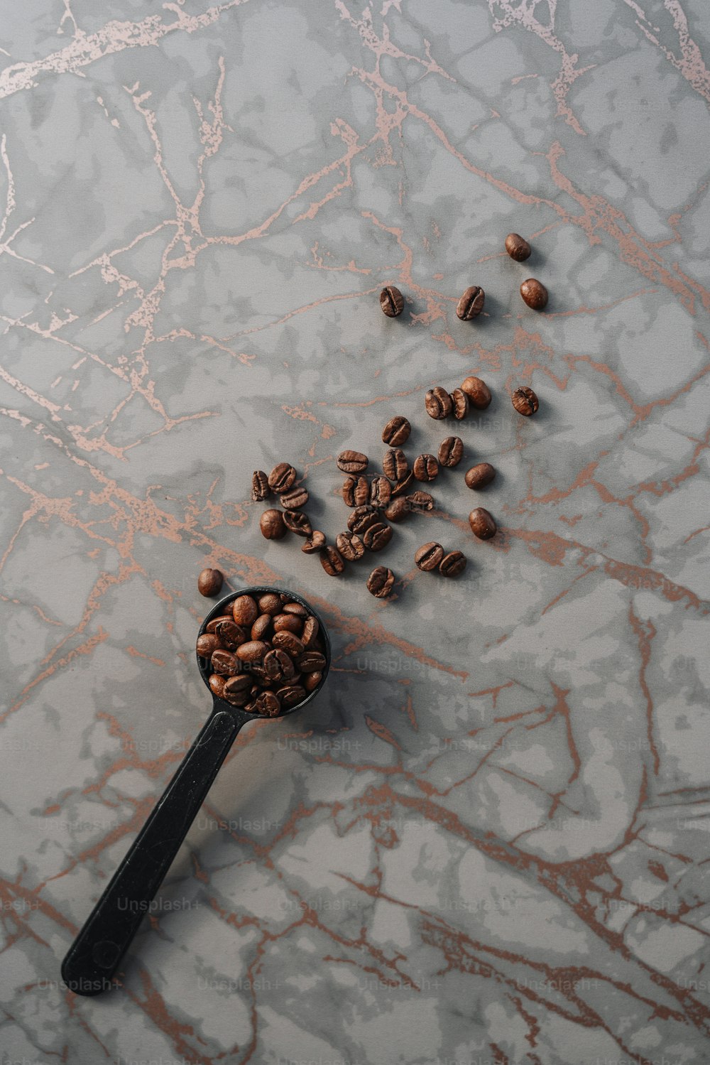 uma colher cheia de grãos de café em uma superfície de mármore