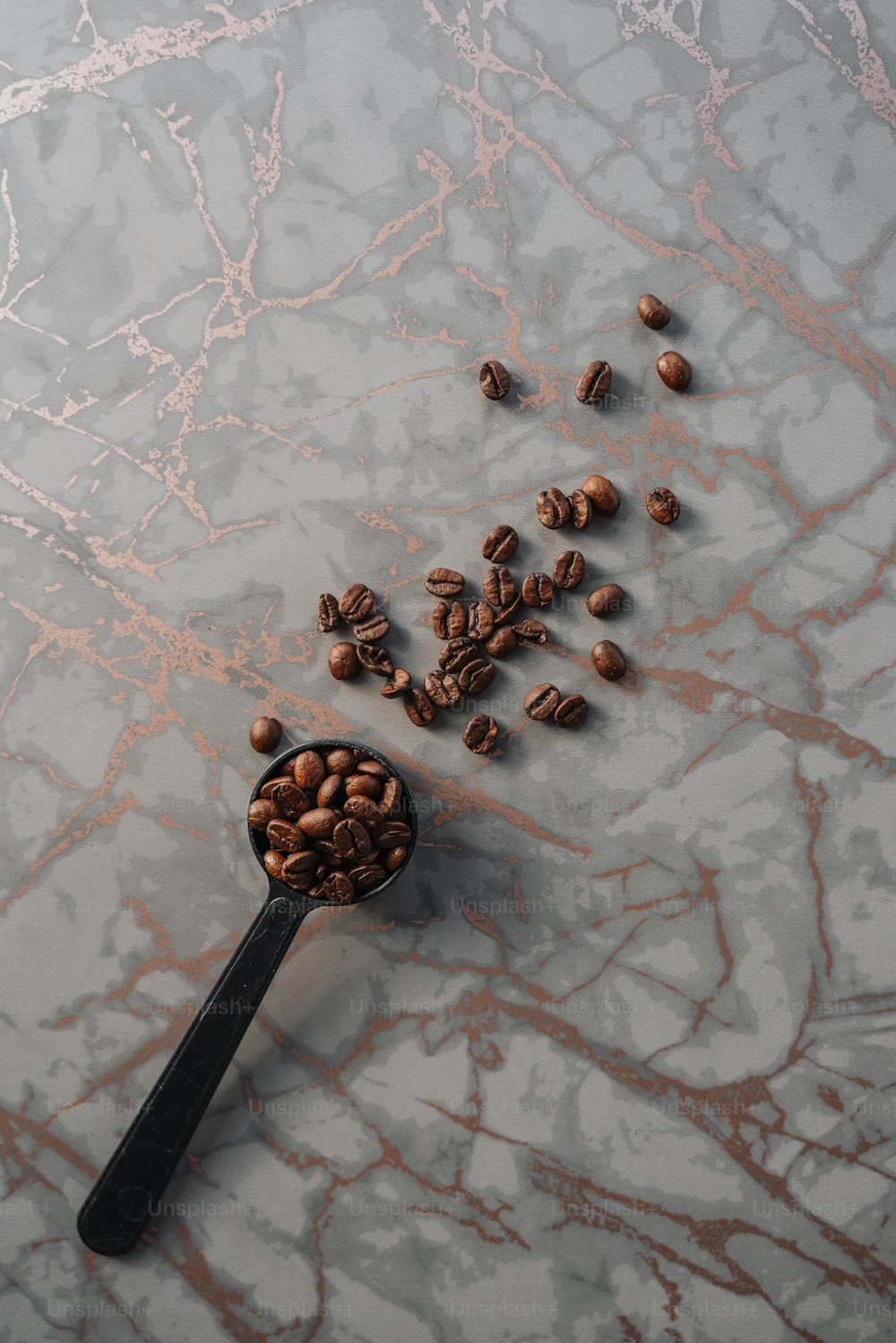 a spoon full of coffee beans on a marble surface
