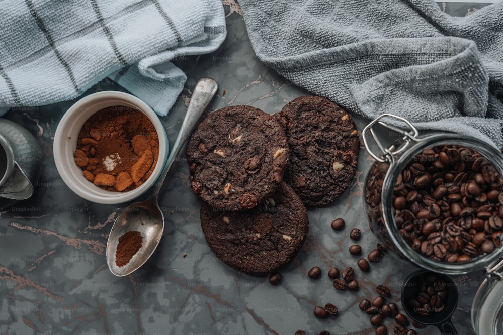 uma mesa coberta com biscoitos de chocolate e grãos de café