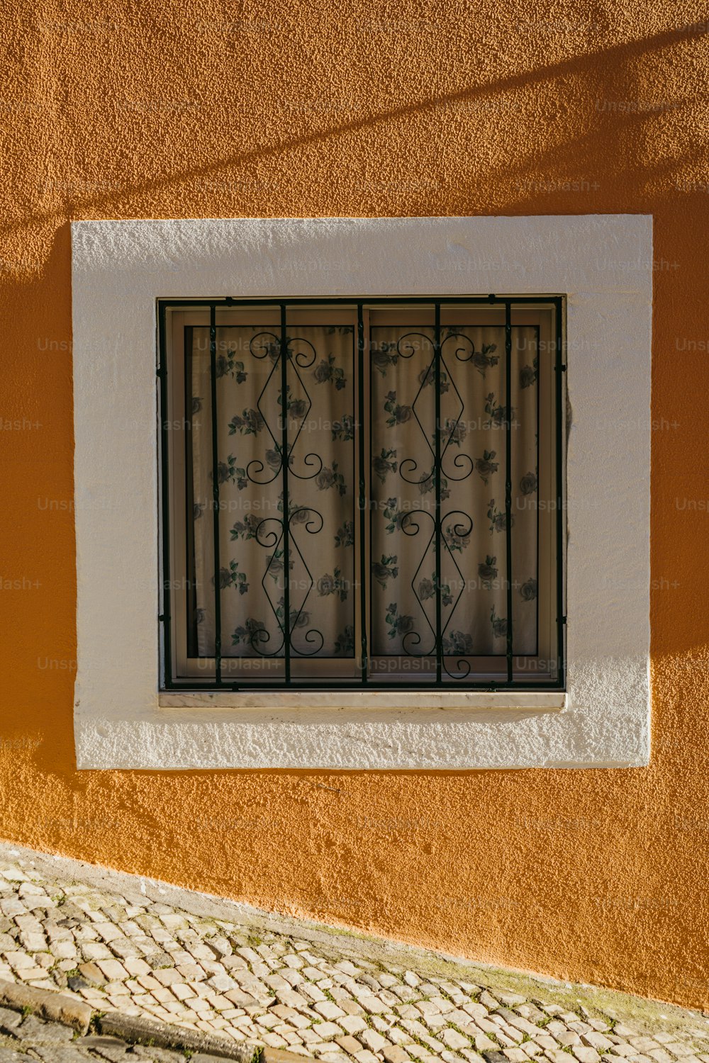 a window on a wall with a wrought iron grill