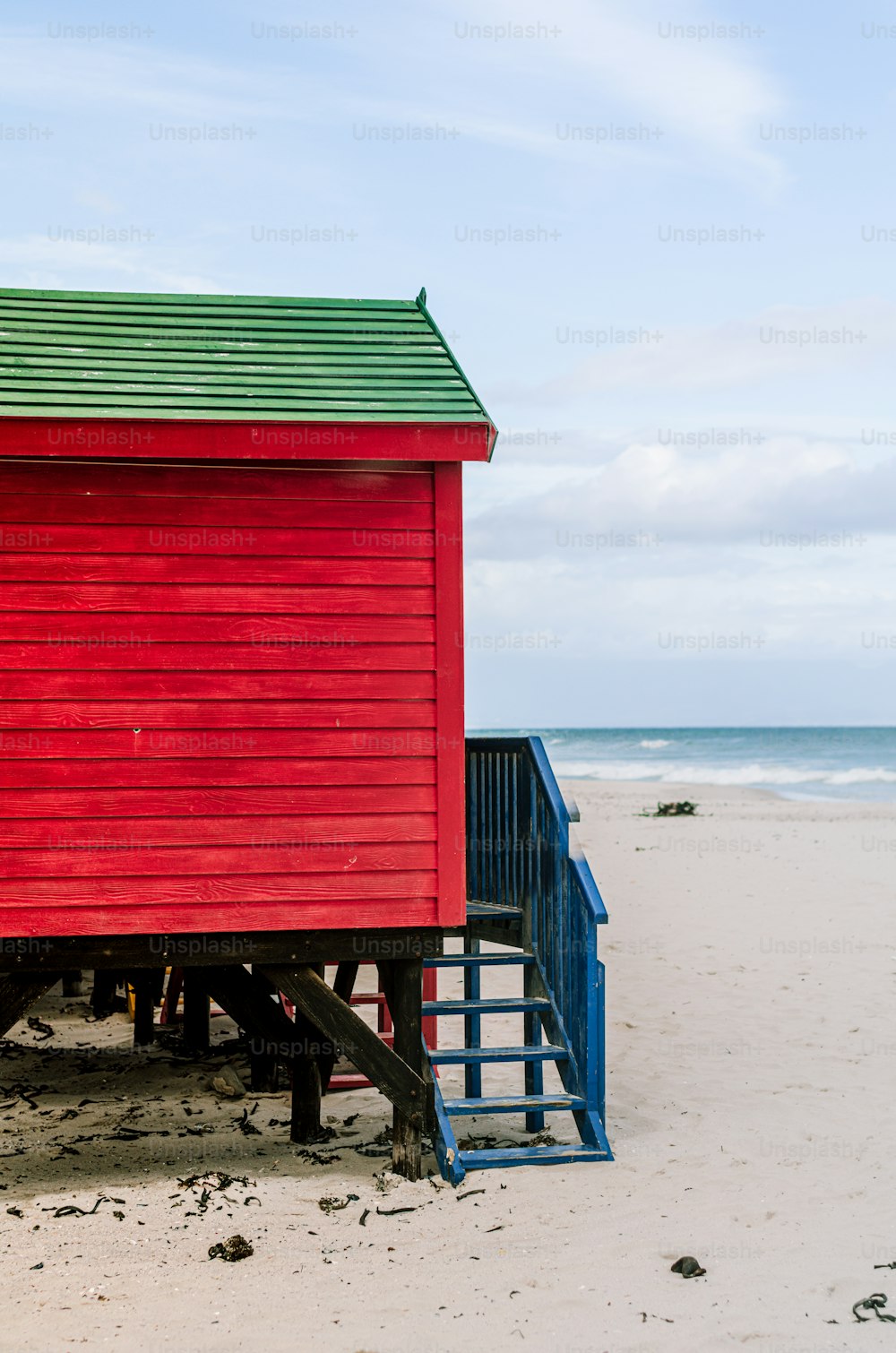 a red building with a green roof on a beach