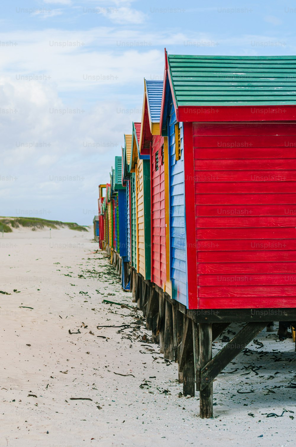 Una fila di capanne sulla spiaggia colorate sedute in cima a una spiaggia sabbiosa