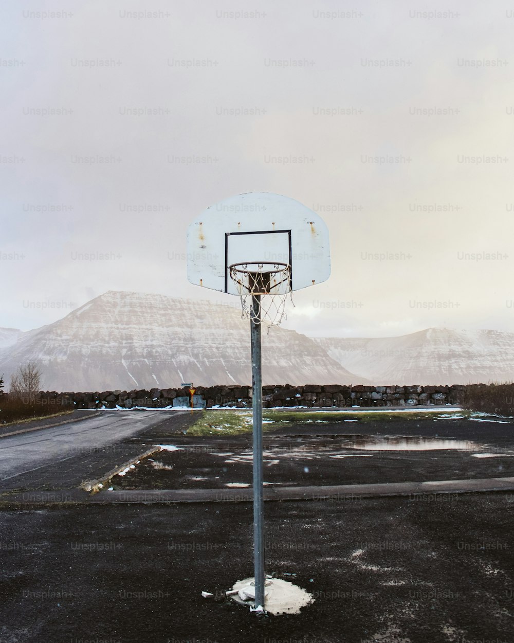 山を背景にした駐車場のバスケットボールのフープ
