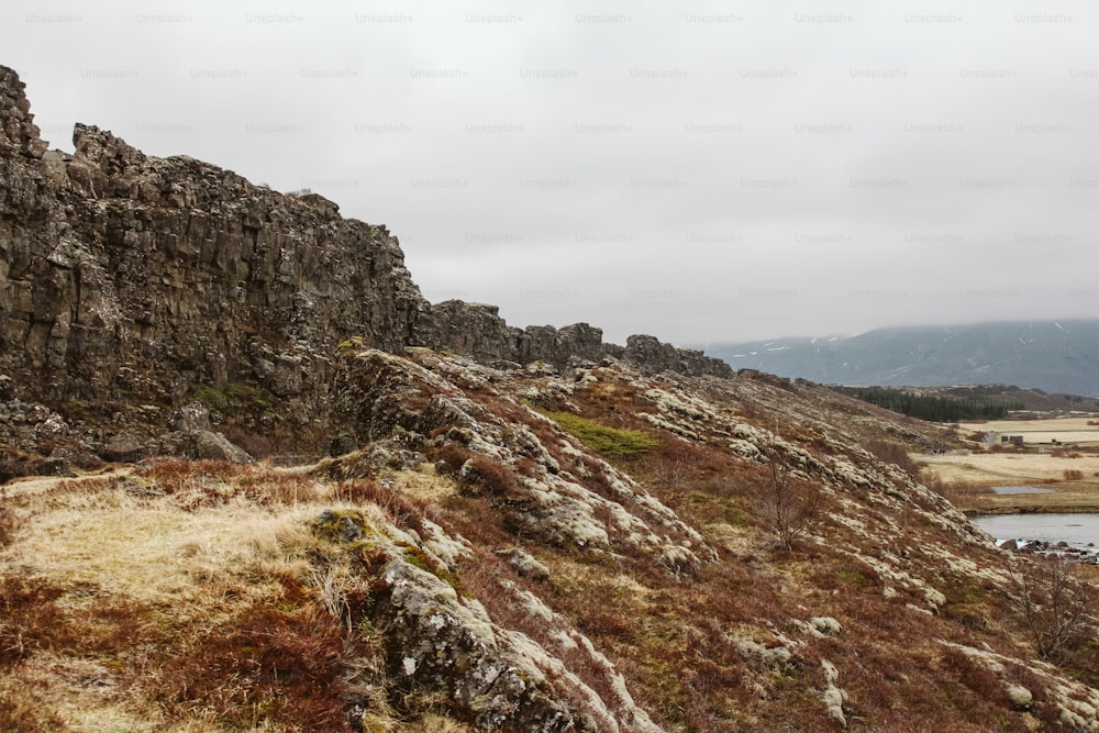 a rocky hill with a body of water in the distance