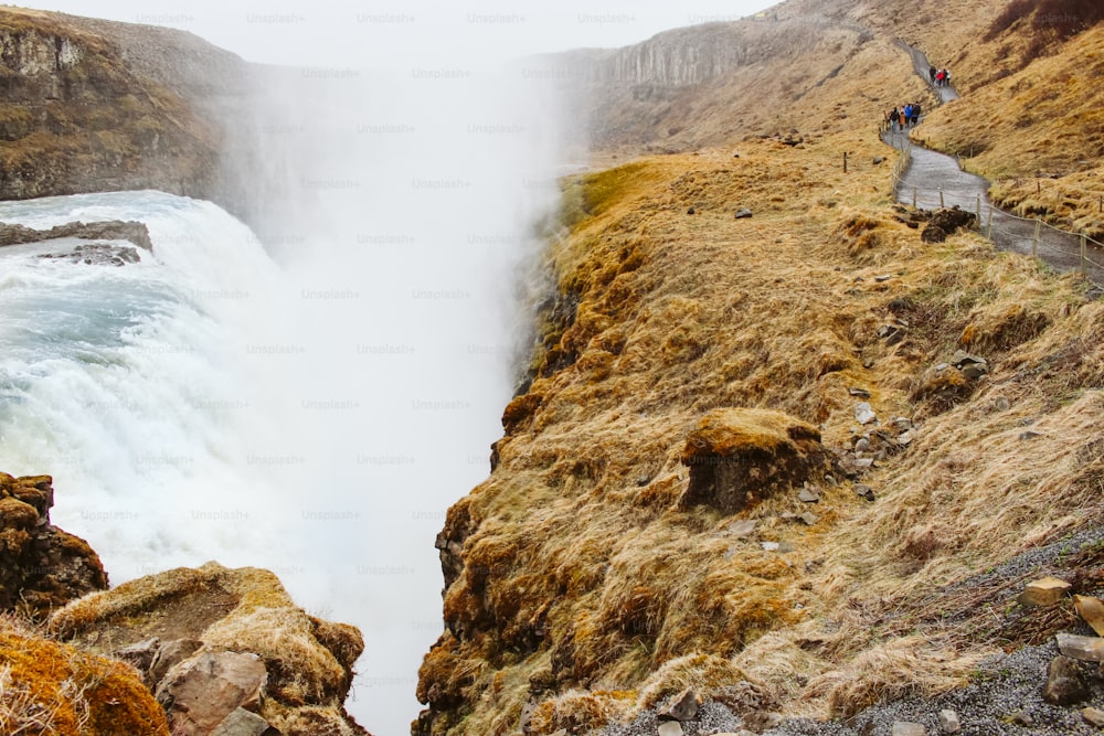 a waterfall with people standing on the side of it