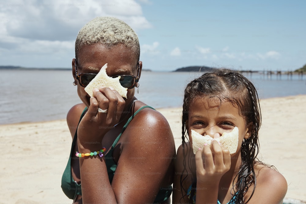 two young girls sitting on the beach eating starfish